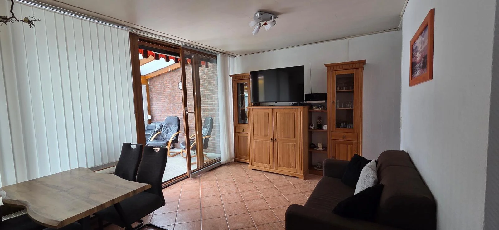 Wohnzimmer mit Flat-TV und Blick zur Terrasse