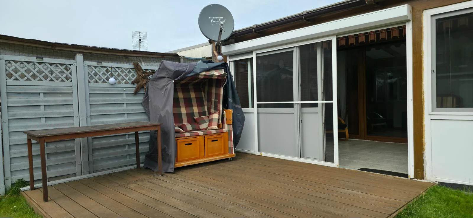 Holzterrasse mit Strandkorb und Wintergarten des Ferienhauses in Bensersiel