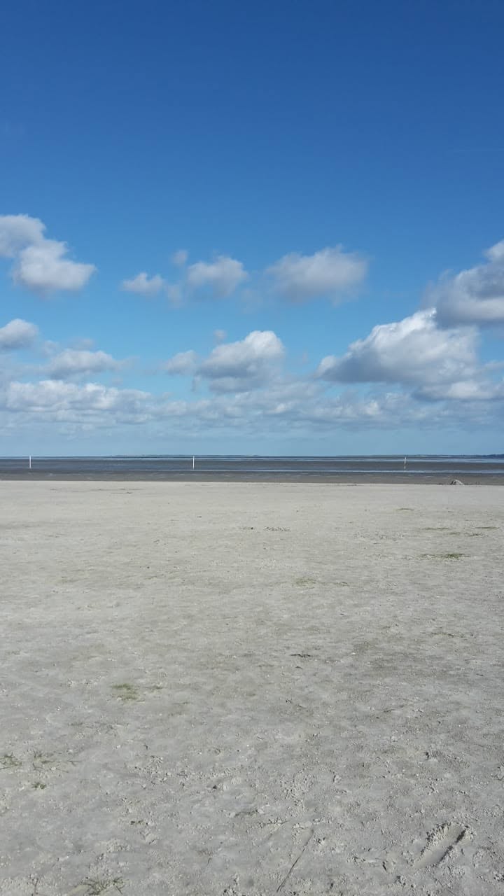 Weiter Sandstrand an der Nordsee bei blauem Himmel